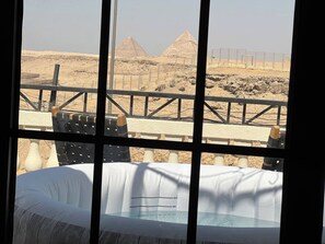 A room with a view of the pyramids, a pool, and a balcony with chairs. - Suspiroo w/skylight and private terrace (Cairo)