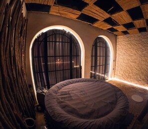 A circular bed in a room with two arched windows, a stone wall, and a ceiling with a checkered pattern. - Suspiroo w/skylight and private terrace (Cairo)