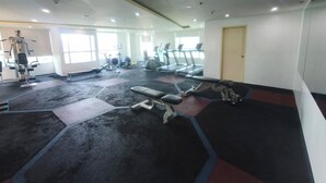 Ein Fitnessstudio mit Laufbändern, Kraftgeräten und Trainingsmatten.