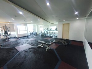 Ein Fitnessstudio mit Laufbändern, Kraftgeräten und Trainingsmatten.