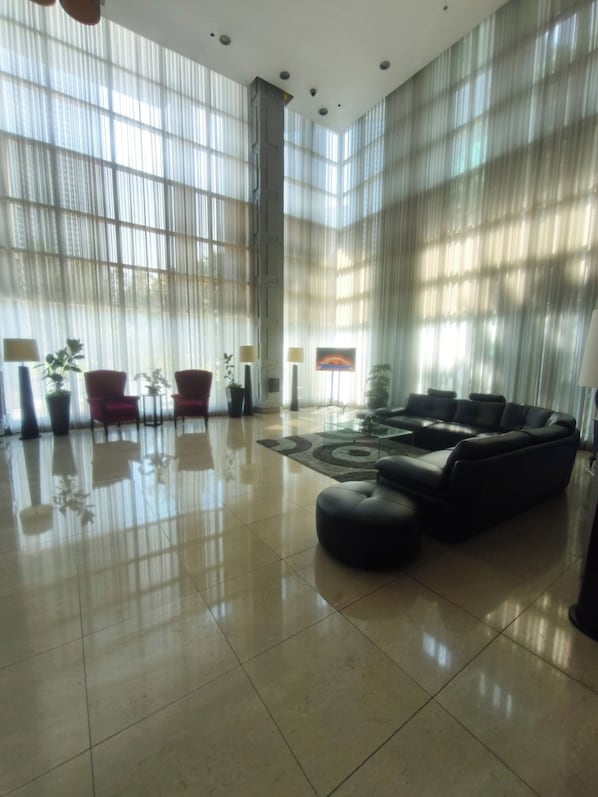 Een ruime lobby met een grote bank, rode stoelen en een bijzettafeltje.