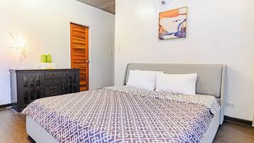 A bedroom with a bed, a nightstand, a lamp, and a painting on the wall.