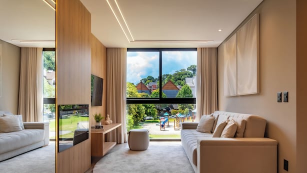 Un salon moderne avec une grande fenêtre, un canapé, un téléviseur et un mur d’accent en bois.