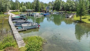 Un port de plaisance avec des bateaux amarrés, une jetée en bois et un petit bâtiment en arrière-plan.