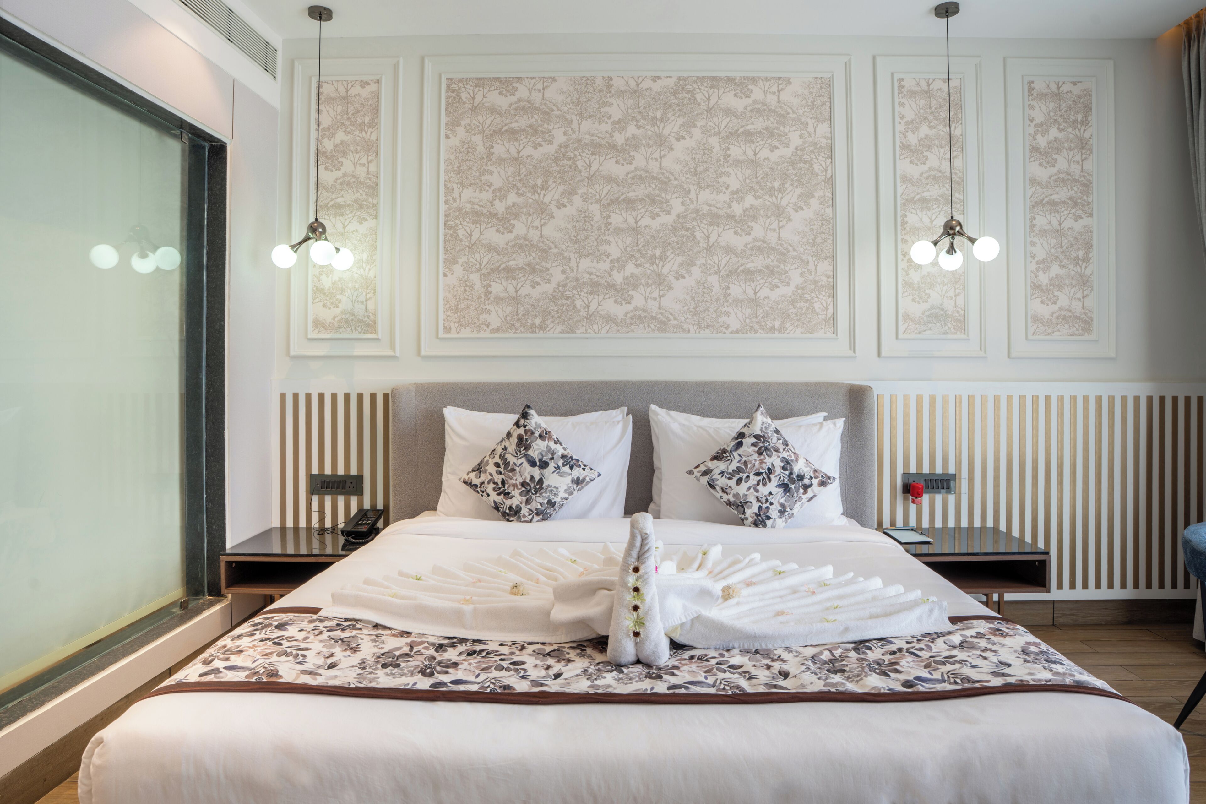 Een hotelkamer met een groot bed, twee nachtkastjes, een telefoon en een raam.