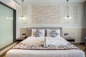Una habitación de hotel con una cama grande, dos mesitas de noche, un teléfono y una ventana.
