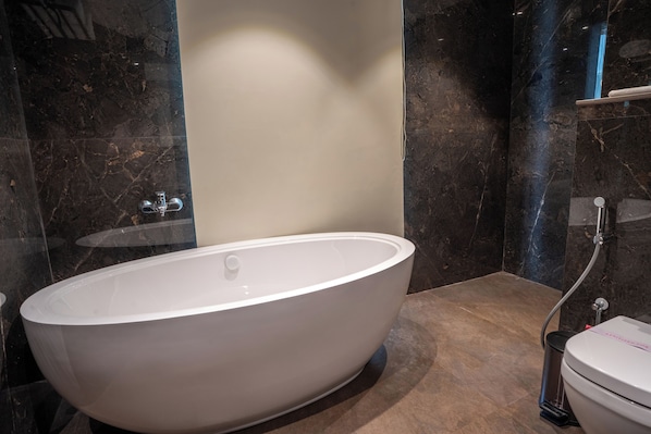A modern bathroom with a freestanding bathtub, a toilet, and a shower area. - Trinity (Siliguri)