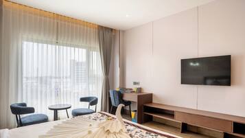 Una habitación de hotel con cama, televisor montado en la pared, escritorio y dos sillas.