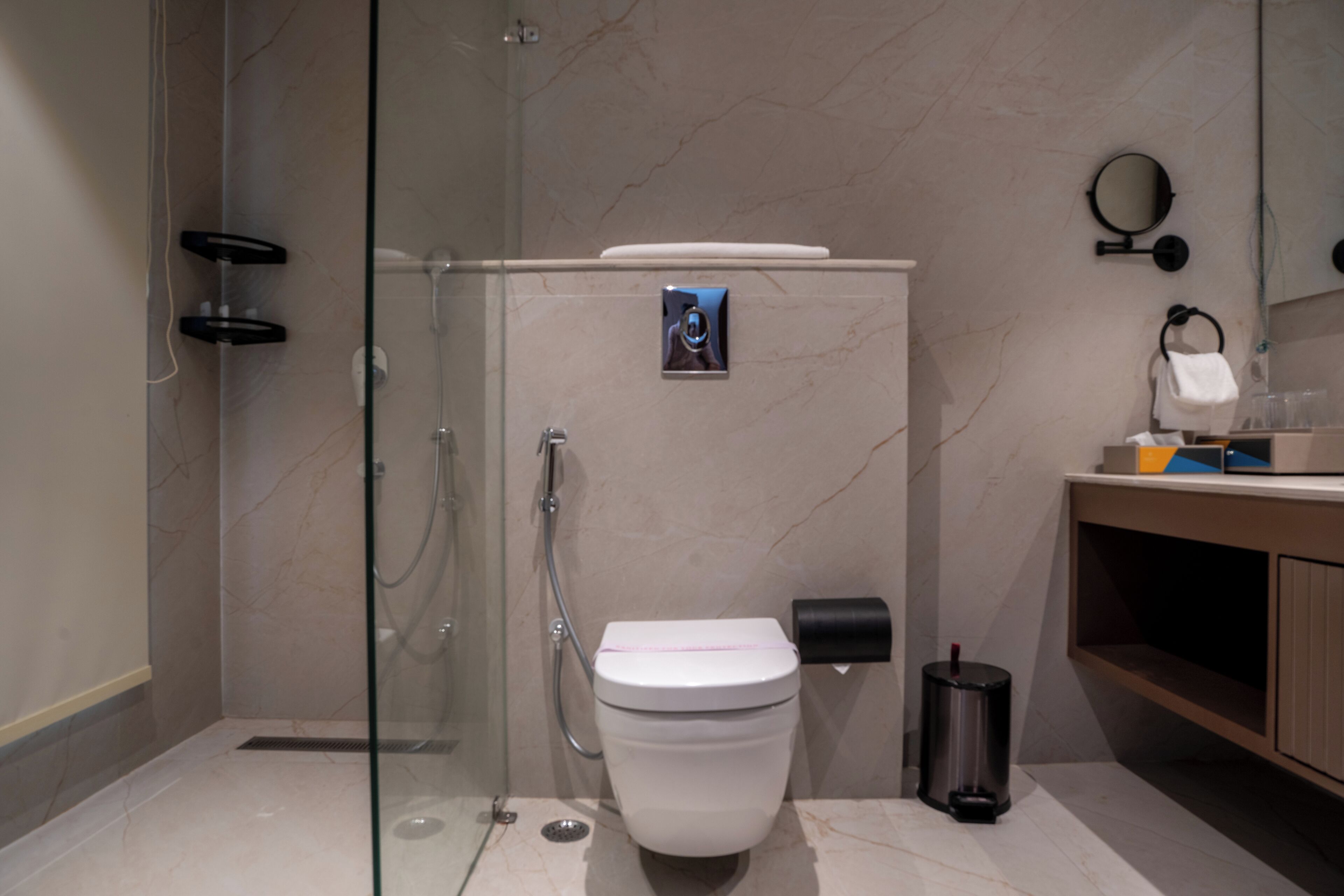 Un baño moderno con ducha envuelta en vidrio, inodoro y tocador con espejo.