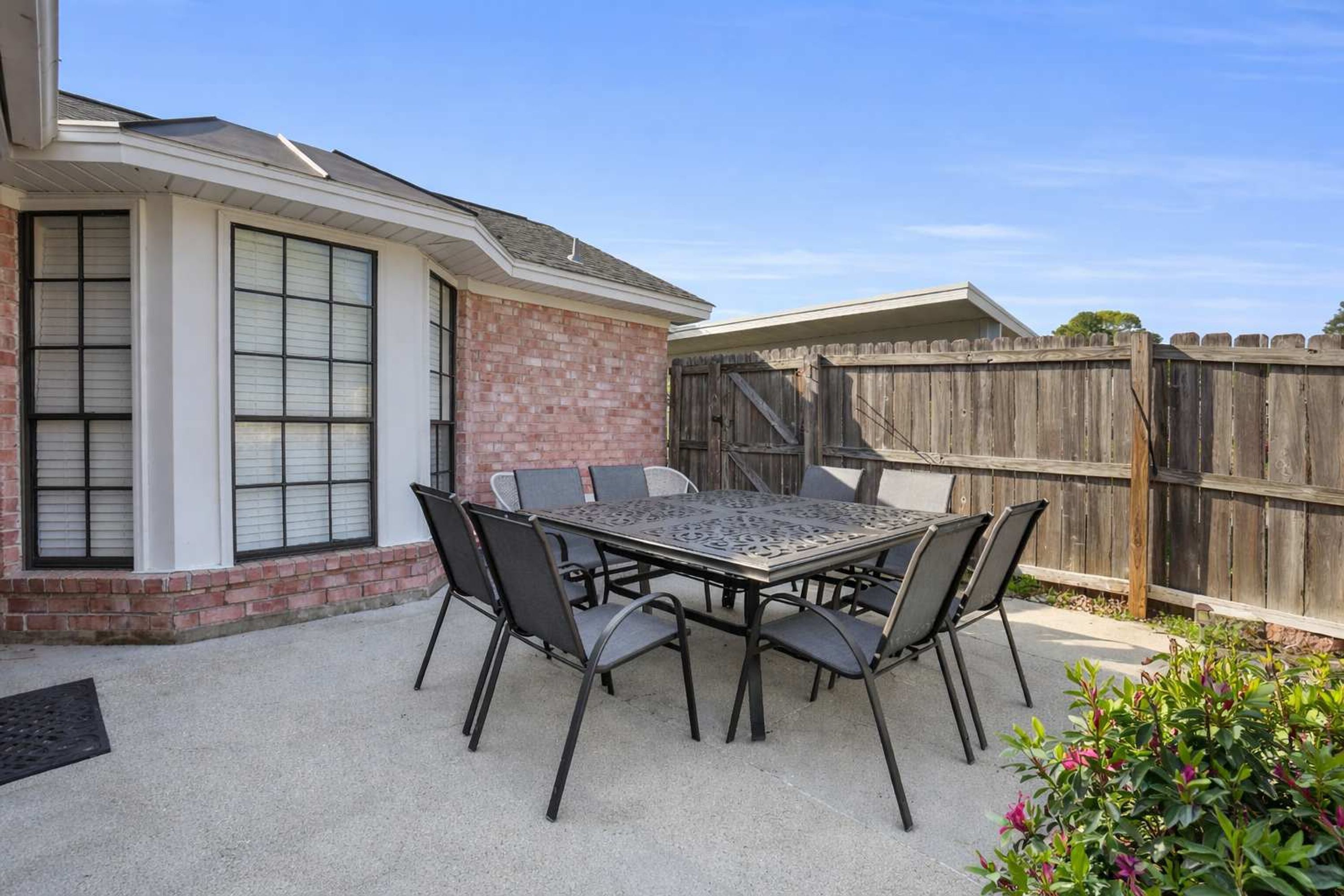 A patio with a metal table and chairs, a brick wall, and a wooden fence.