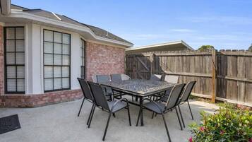 A patio with a metal table and chairs, a brick wall, and a wooden fence.