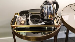 A tray with a coffee maker, cups, and a small container on a glass table. - Cuevas Home Relais  (Naples)