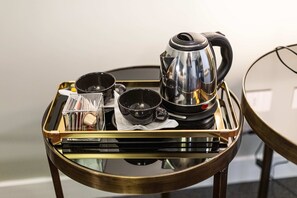 Ein Tablett mit einer Kaffeemaschine, Tassen und einem kleinen Behälter auf einem Glastisch.