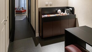 A modern hotel room with a kitchenette, a dining area, and a hallway leading to a bedroom. - Cuevas Home Relais  (Naples)
