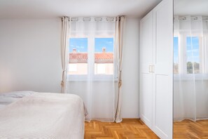 A bedroom with a bed, a wardrobe, and a window with curtains. - Apt Xenia Walk To Beach /w Balcony (Medulin)