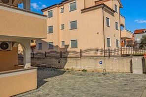 Ein Gebäude mit beige farbenem Mauerwerk, zahlreichen Fenstern und einem ehrfurchtgebietenden Eingangstor.