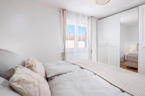 Ein Schlafzimmer mit einem Bett, einem Kleiderschrank und einem Fenster mit Vorhängen.