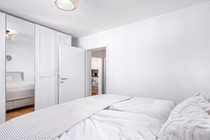 Ein schlicht eingerichtetes Schlafzimmer mit einem großen Bett, einem Kleiderschrank und einer Tür zu einem Badezimmer.