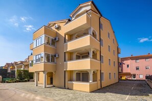 Ein mehrgeschossiges Wohngebäude mit Balkonen, Klimaanlagen und einem gepflasterten Innenhof.
