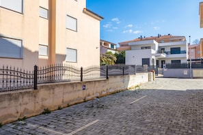 A paved courtyard with a metal fence, a parking sign, and buildings with balconies. - Apt Xenia Walk To Beach /w Balcony (Medulin)