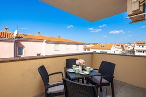 Ein Balkon mit Tisch für zwei Personen, Stühlen und einem Blumenstrauß.