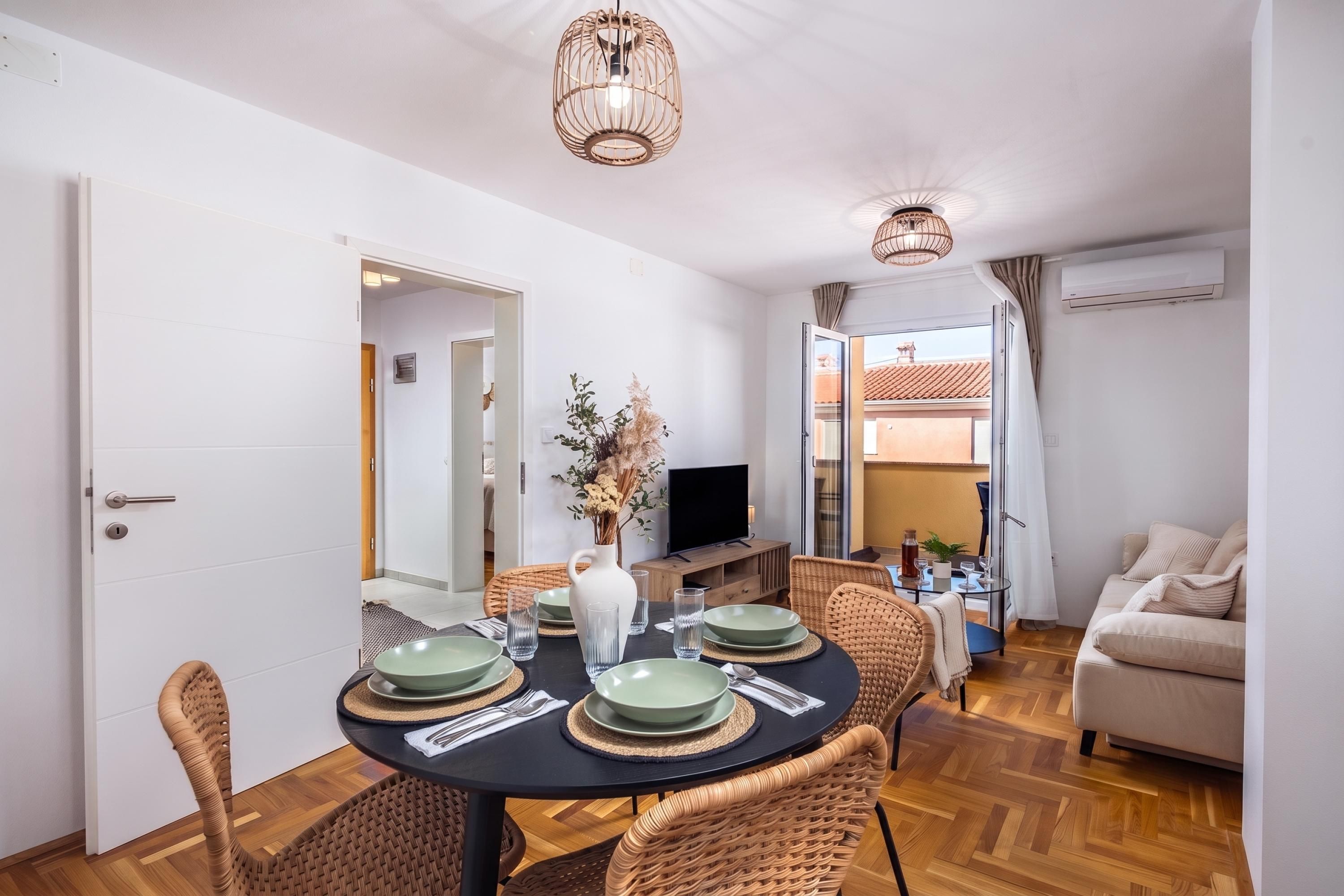 A dining area with a round table, chairs, and a television in the background.