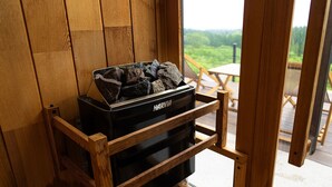 A Harvia wood stove in a wooden interior with a view of a deck and greenery outside. - FOG VILLA&SPA (Kirishima)