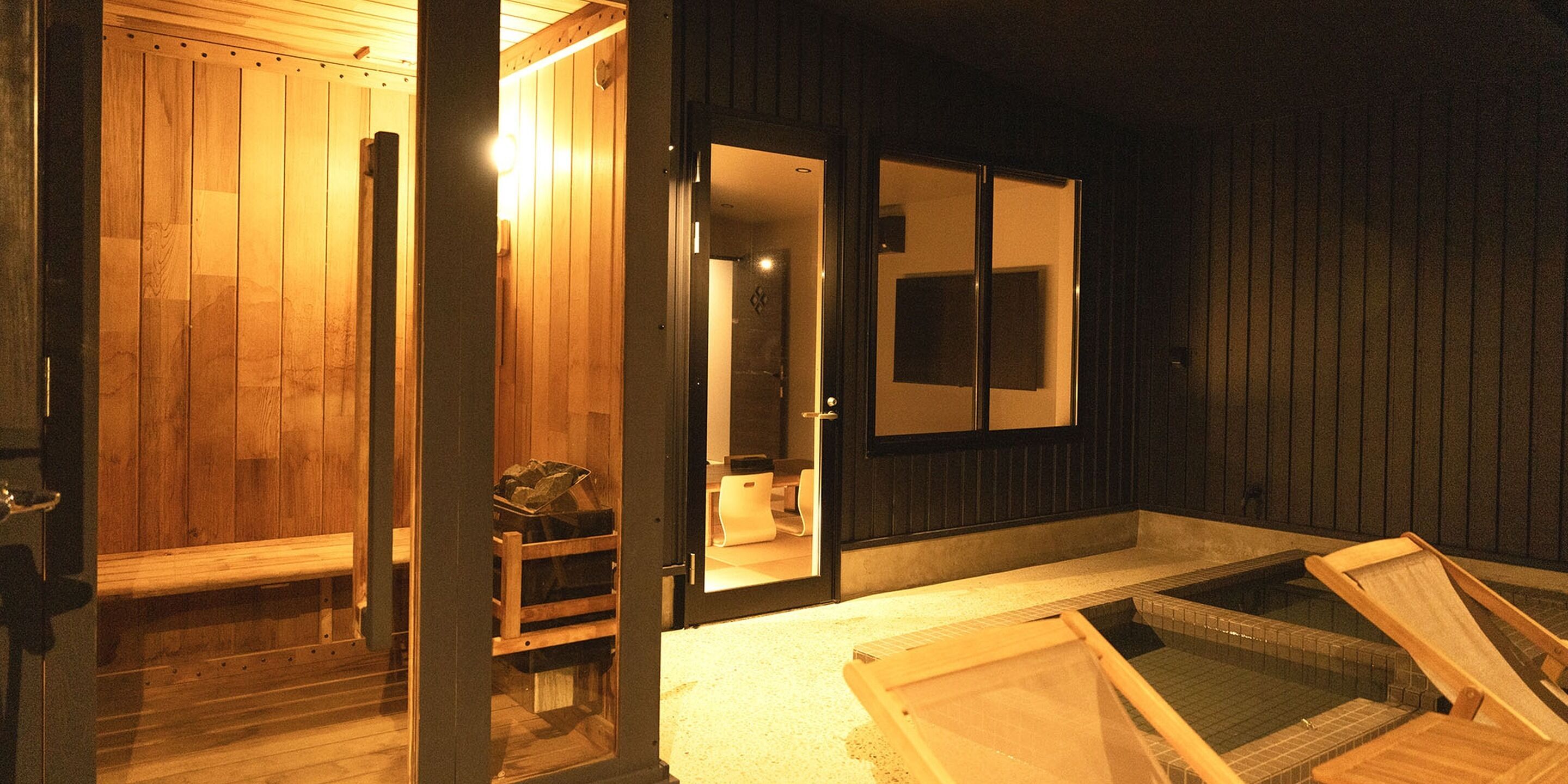 A sauna room with wooden benches, a bench with a bag, and a small window.