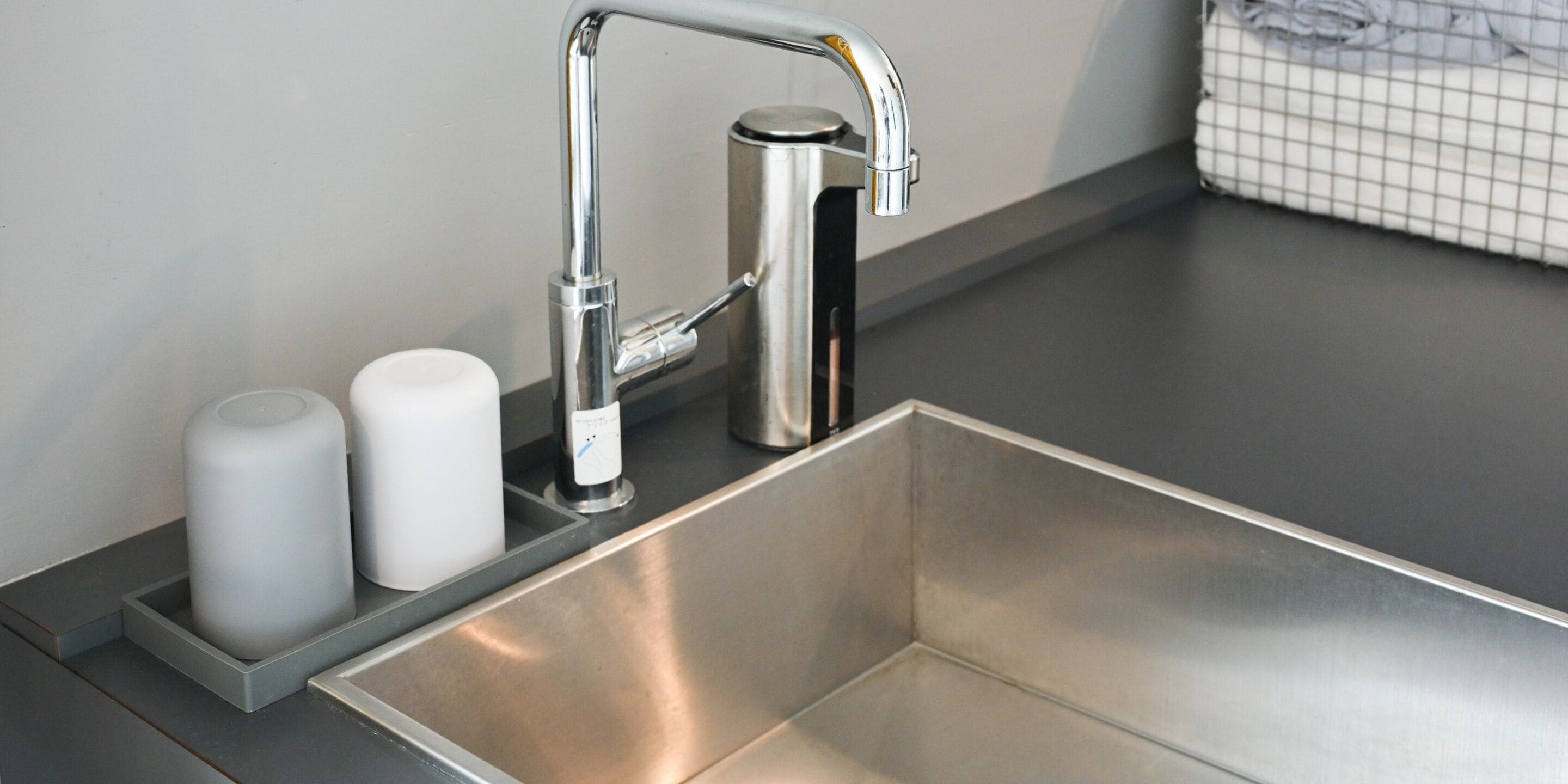 Un évier en acier inoxydable doté d’un robinet moderne, d’un distributeur de savon et d’un porte-brosse à dents.