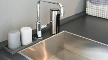 Un évier en acier inoxydable doté d’un robinet moderne, d’un distributeur de savon et d’un porte-brosse à dents.