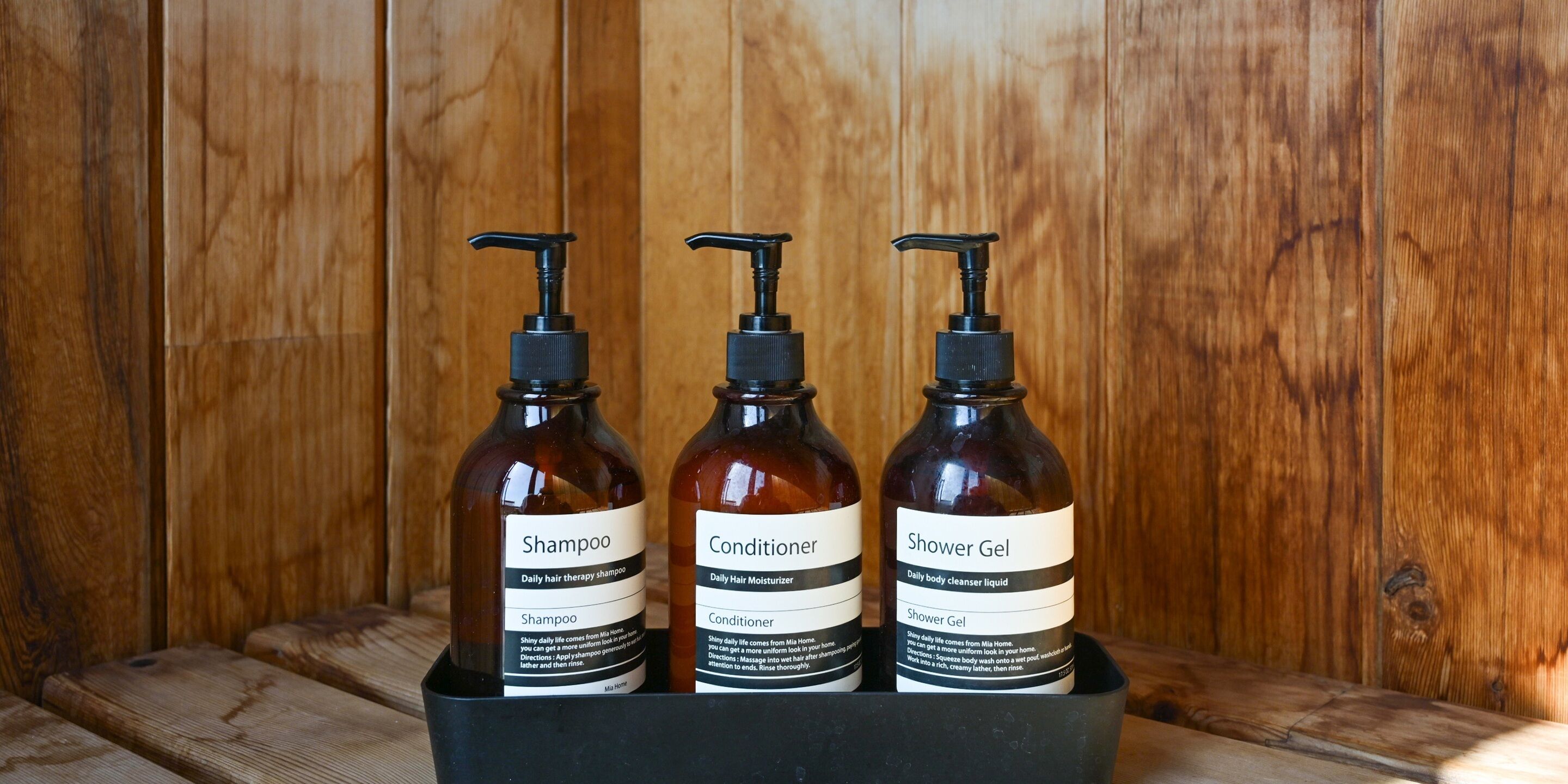 Three bottles of personal care products in a black container.