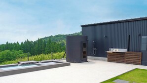 A modern outdoor pool area with a large water heater, a wooden bench, and a metal sink against a dark building. - FOG VILLA&SPA (Kirishima)