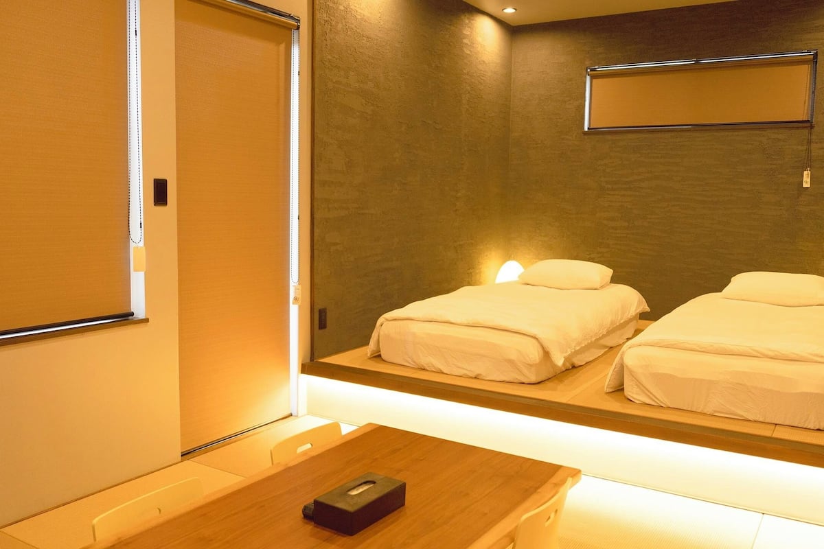 A hotel room with a bed, bedside table, and a mirror.