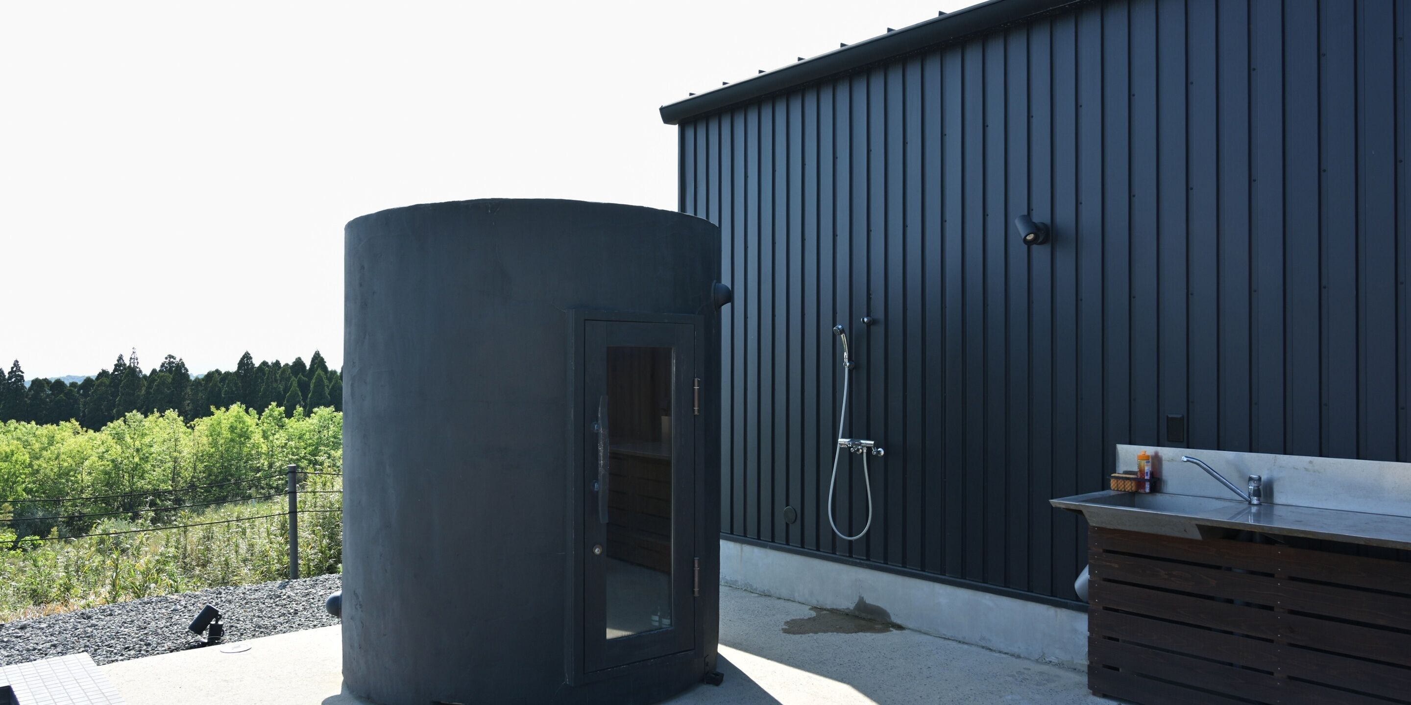 A sauna next to a building with a shower and a sink.