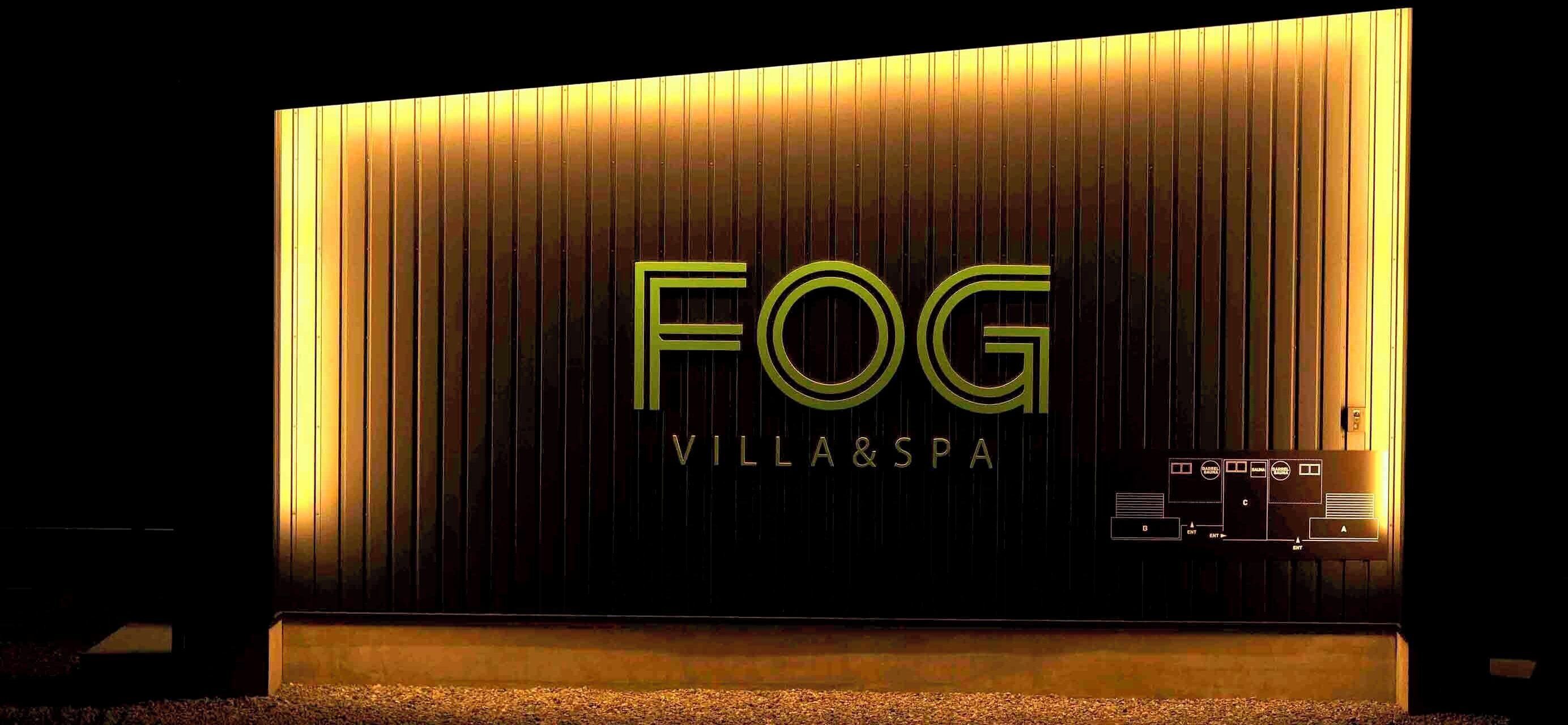 Fachada de un edificio con el texto iluminado 'FOG VILLA&SPA'.