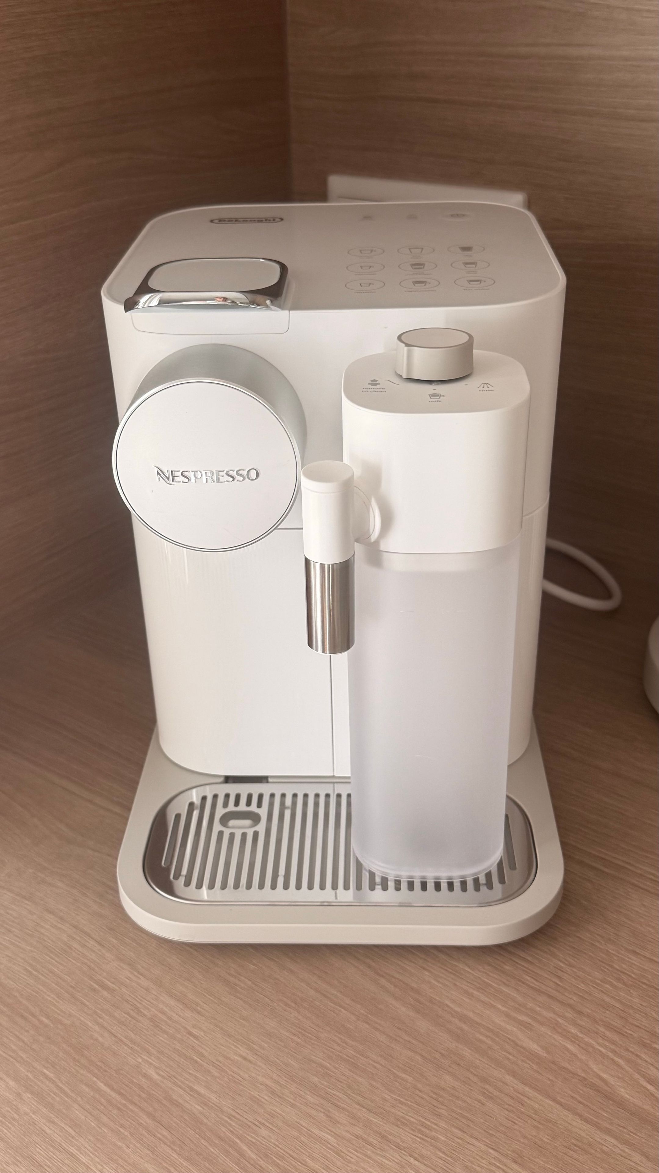 Eine weiße Nespresso-Kaffeemaschine mit Wassertank und Auffangschale.