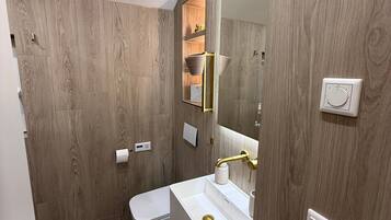 Un baño moderno con pared de madera, lavamanos blanco y un inodoro.