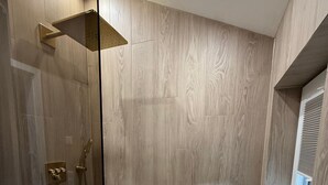 A modern bathroom with a shower, a vanity with a mirror, and a window.