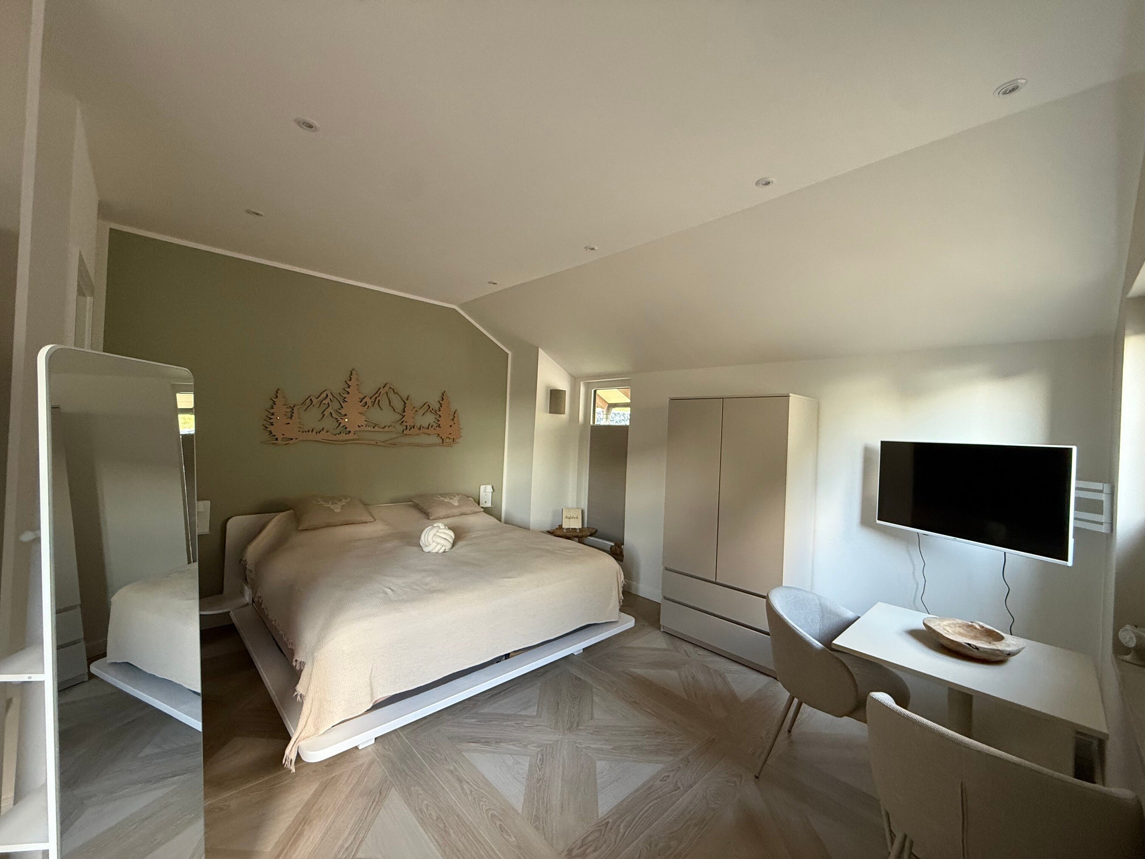 Ein Schlafzimmer mit Bett, Schreibtisch, Stuhl, Fernseher und Kleiderschrank.