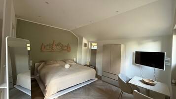 Ein Schlafzimmer mit Bett, Schreibtisch, Stuhl, Fernseher und Kleiderschrank.