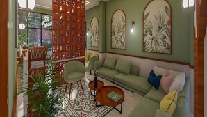 Ein Wohnzimmer mit einer Couch, Sesseln, einem Couchtisch, einem dekorativen Raumteiler und Wandbildern.