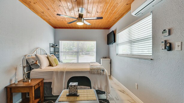 A bedroom with a bed, bedside table, lamp, bedside console, and a ceiling fan. - 1 Mi to Midtown & Stadium! Couple's Haven in Tampa (Tampa)