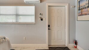 A hallway with a white door, a thermostat, and a fire extinguisher. - 1 Mi to Midtown & Stadium! Couple's Haven in Tampa (Tampa)