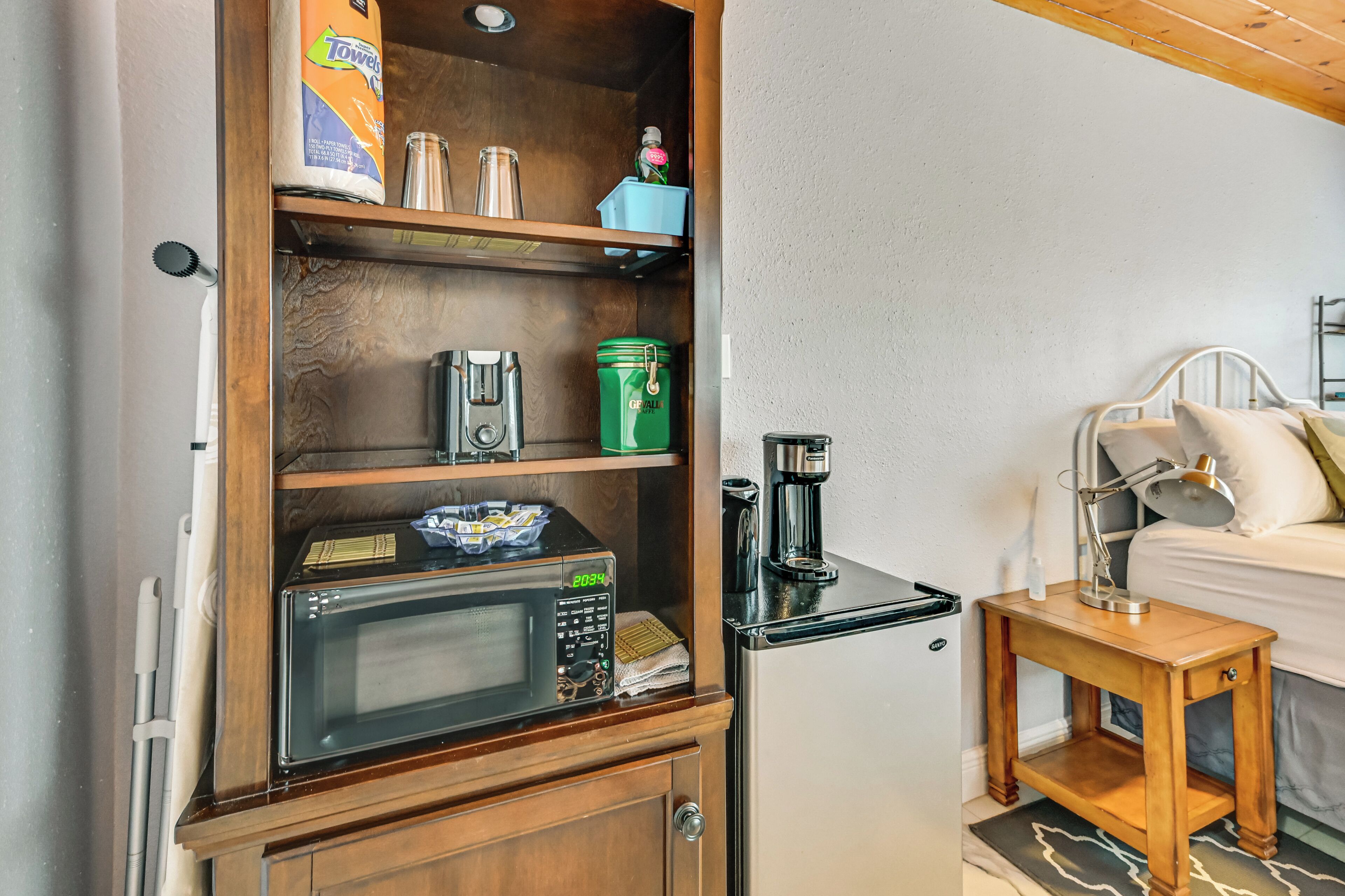 Une petite cuisine équipée d’un four à micro-ondes, d’une machine à café et d’étagères de rangement.