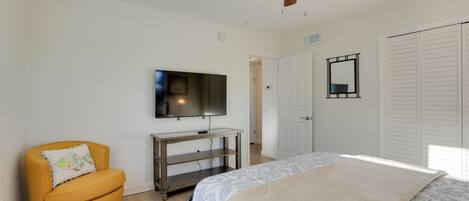 A bedroom with a bed, a TV, a ceiling fan, a chair, and a wardrobe.