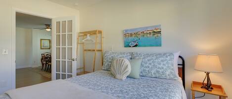 Un dormitorio con cama, un cuadro, una mesita de noche de madera y un ventilador de techo.