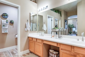A bathroom with a large mirror, wooden vanity, and a sink. - Patio & Home Gym! Augusta Ranch Golf Home (Mesa)