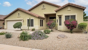 A two-story house with a garage, a small front yard with gravel, and various shrubs and plants. - Patio & Home Gym! Augusta Ranch Golf Home (Mesa)