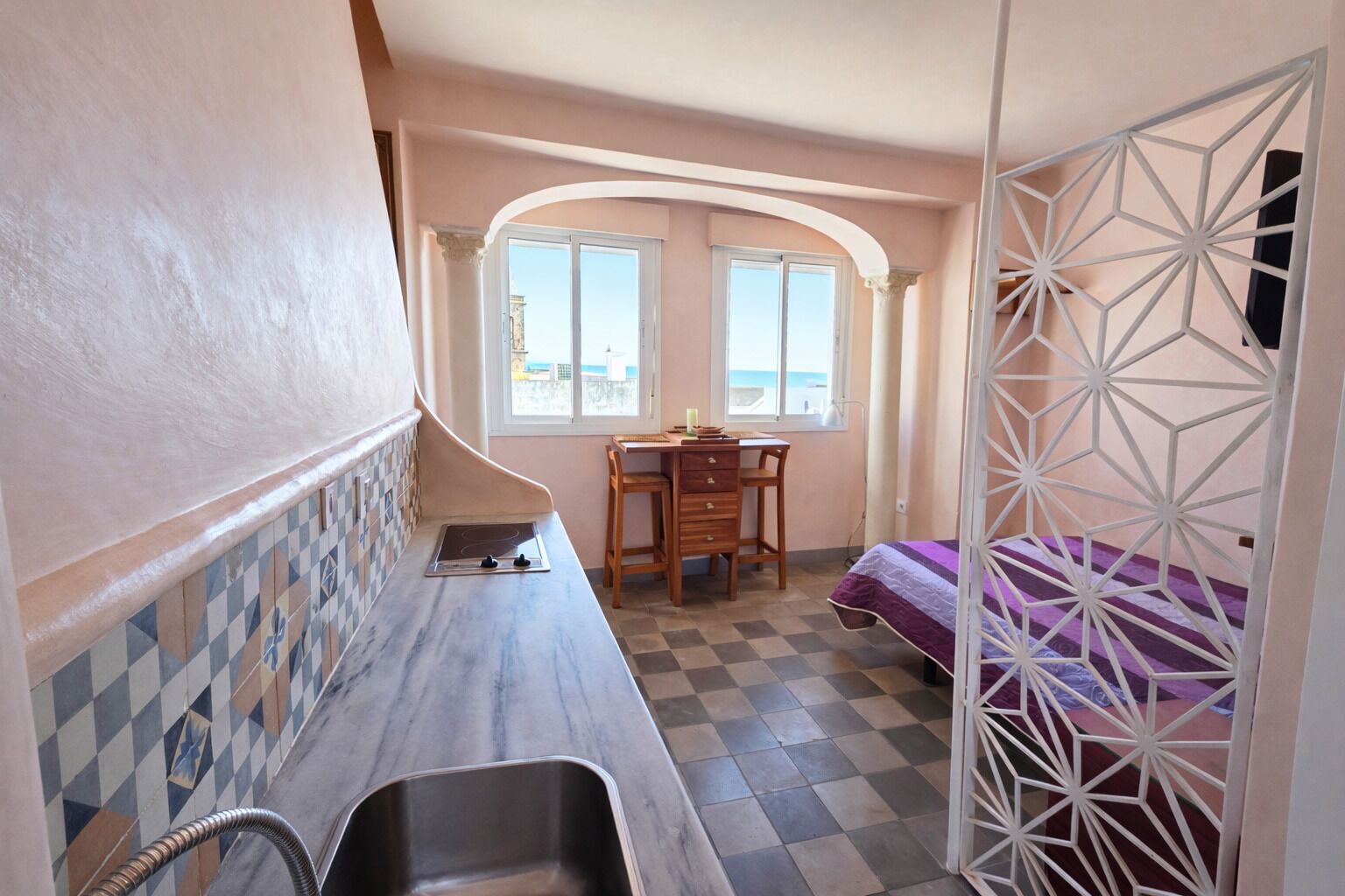 Une pièce de taille modeste comprenant un coin cuisine, une table à manger et un lit.