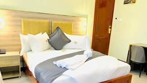 A neatly made bed with a wooden headboard, a bedside table, and a chair.
